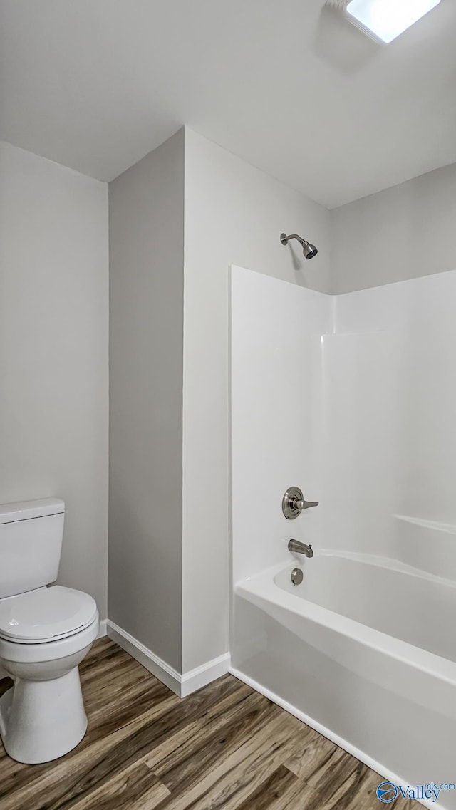 bathroom with toilet, wood-type flooring, and shower / tub combination