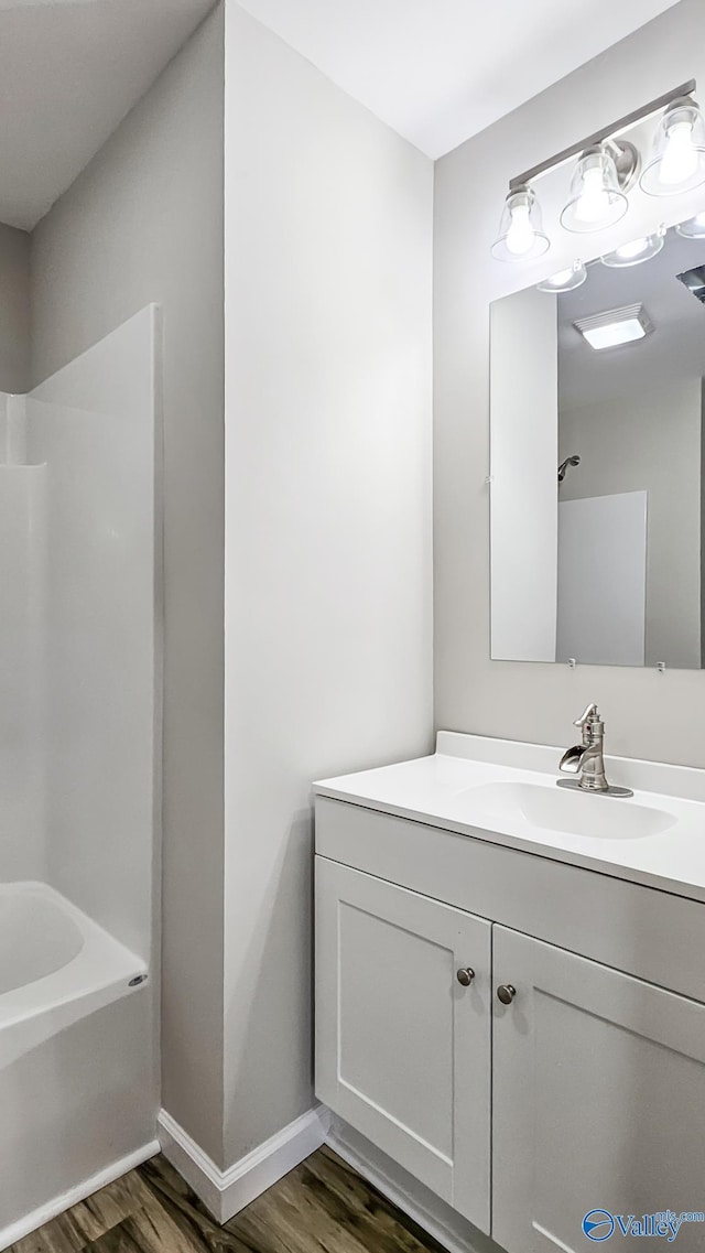 bathroom with hardwood / wood-style flooring, vanity, and tub / shower combination