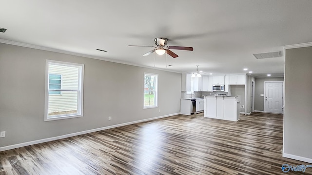 unfurnished living room featuring ornamental molding, a wealth of natural light, dark wood-type flooring, and sink