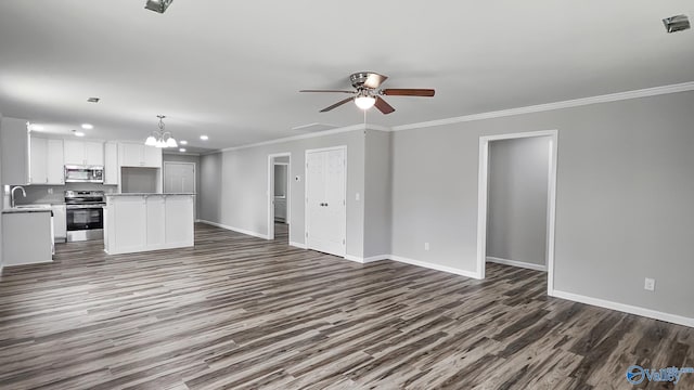 unfurnished living room with sink, ceiling fan with notable chandelier, dark hardwood / wood-style flooring, and crown molding