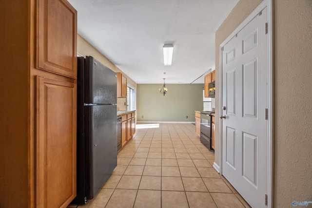 kitchen featuring brown cabinets, black appliances, light tile patterned flooring, baseboards, and a chandelier