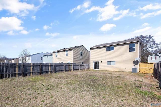 rear view of property with central AC unit, a lawn, and a fenced backyard