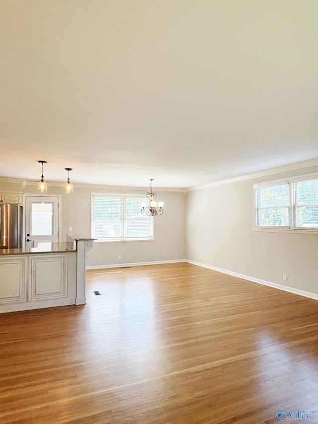 5627 SW Alta Dena St, Huntsville, AL 35802 - unfurnished living room with crown molding, light wood-style floors, a chandelier, healthy amount of natural light, and baseboards