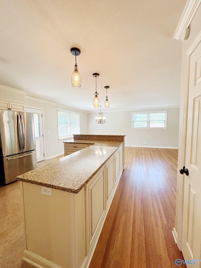 5627 SW Alta Dena St, Huntsville, AL 35802 - kitchen with freestanding refrigerator, plenty of natural light, light stone countertops, light wood-type flooring, and crown molding