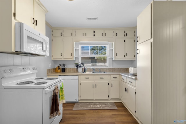 kitchen featuring visible vents, a sink, dark wood finished floors, white appliances, and light countertops