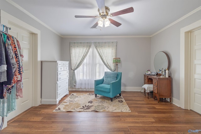 living area with crown molding, wood finished floors, baseboards, and ceiling fan