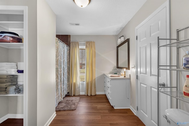 hall with baseboards, visible vents, dark wood-style flooring, and a sink