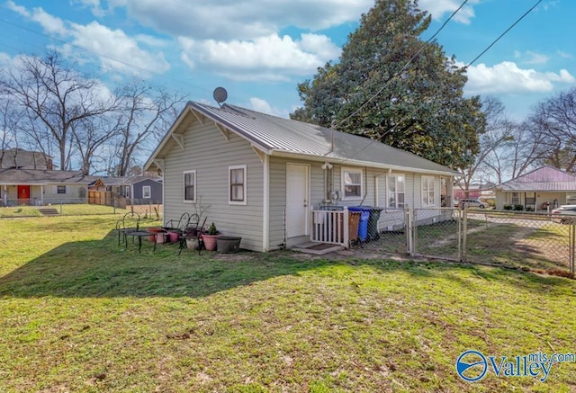 rear view of house with a gate, metal roof, a yard, and fence