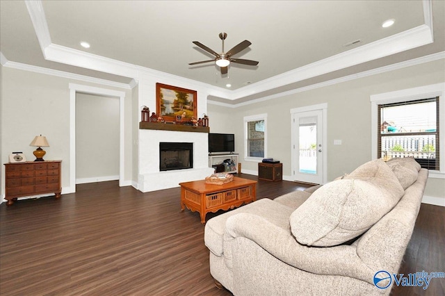 living room featuring a raised ceiling, dark hardwood / wood-style flooring, and crown molding