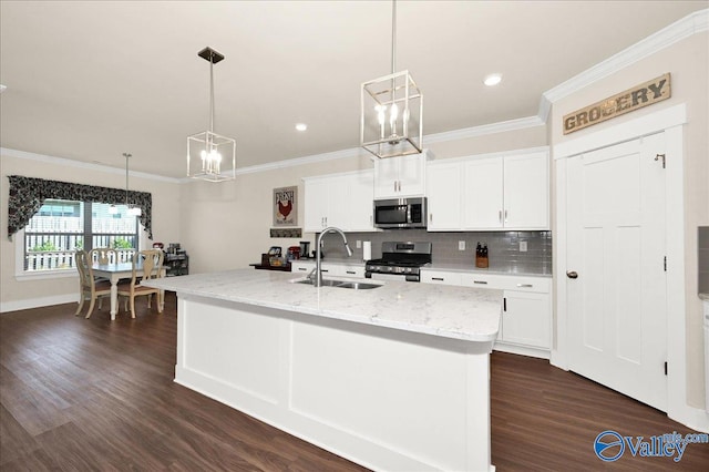 kitchen with pendant lighting, dark hardwood / wood-style floors, stainless steel appliances, and a kitchen island with sink