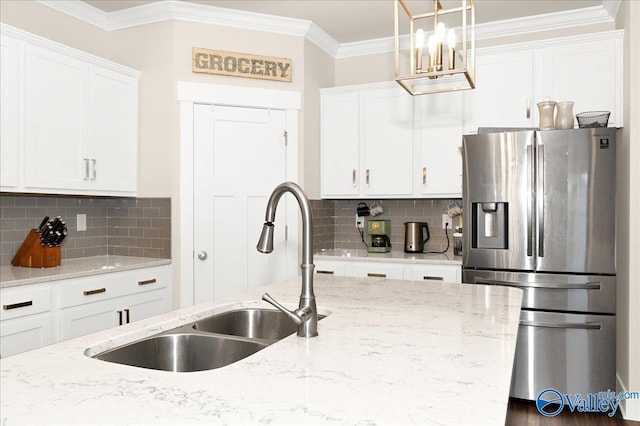 kitchen with light stone countertops, stainless steel fridge, white cabinetry, and sink