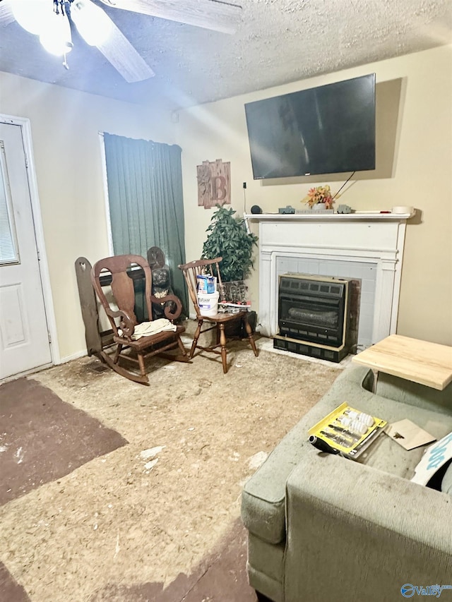 living room featuring a tile fireplace, ceiling fan, and a textured ceiling