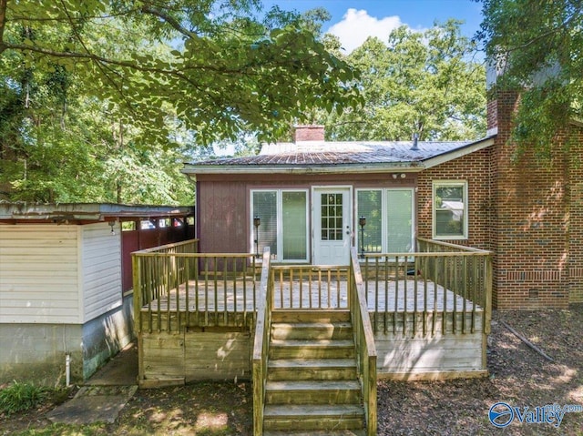 rear view of house featuring a wooden deck, crawl space, and a chimney