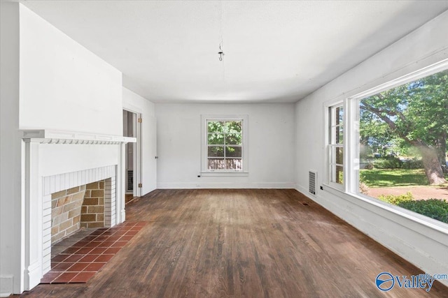 unfurnished living room featuring a fireplace with flush hearth, dark wood-style floors, and baseboards