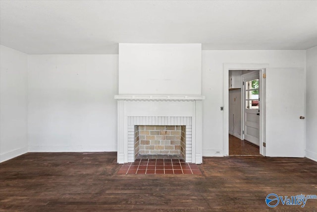 unfurnished living room with dark hardwood / wood-style flooring and a brick fireplace