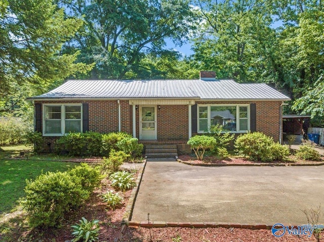 single story home with brick siding, a chimney, and metal roof