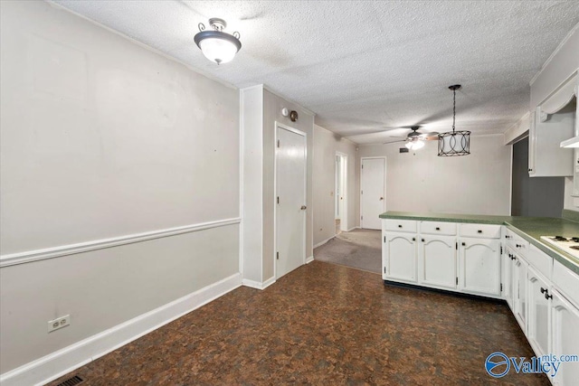 kitchen featuring baseboards, a peninsula, ceiling fan, white cabinets, and a textured ceiling