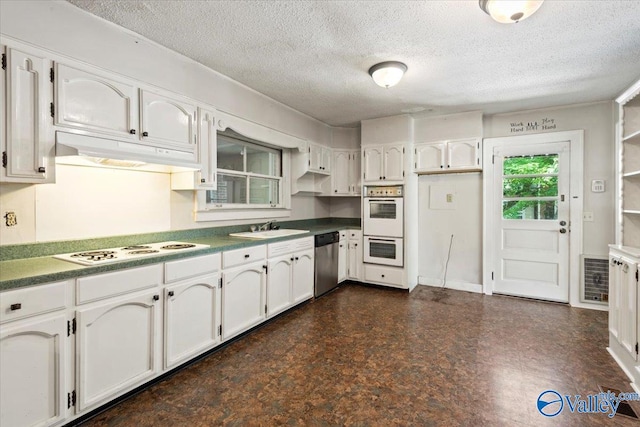 kitchen featuring white cabinetry, a textured ceiling, dark tile patterned floors, and white appliances