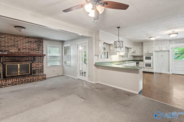 kitchen featuring a brick fireplace, a textured ceiling, a peninsula, and ceiling fan