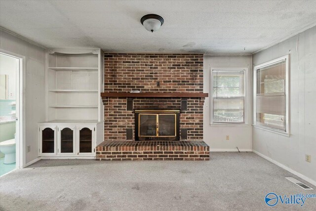 unfurnished living room featuring a textured ceiling, a brick fireplace, and carpet flooring