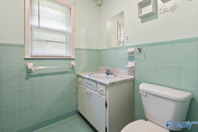 half bathroom with a wainscoted wall, vanity, toilet, and tile walls