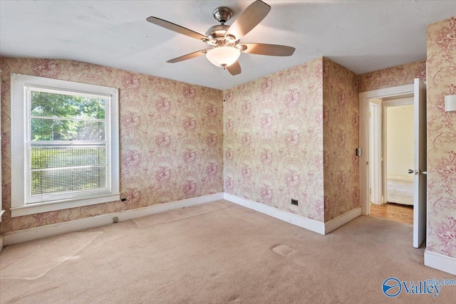 carpeted empty room featuring wallpapered walls, a ceiling fan, and baseboards