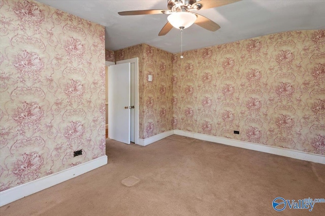 carpeted empty room with baseboards, wallpapered walls, and a ceiling fan