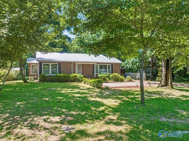 ranch-style home featuring metal roof, brick siding, and a front yard
