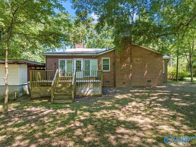 back of property featuring a deck and a lawn