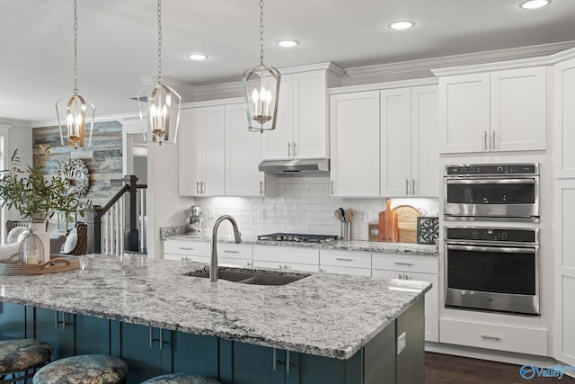 155 Holbrook Dr, Huntsville, AL 35806 - kitchen with stainless steel appliances, under cabinet range hood, crown molding, a kitchen bar, and white cabinetry