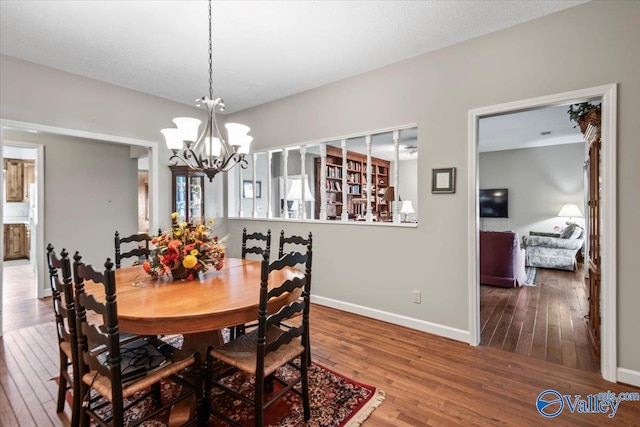 dining room featuring baseboards, hardwood / wood-style flooring, and an inviting chandelier