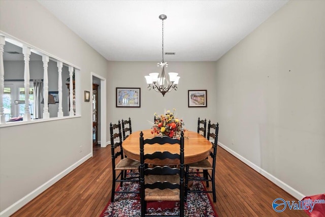 dining area featuring dark wood-style floors, an inviting chandelier, visible vents, and baseboards