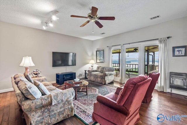 living area featuring a textured ceiling, dark wood-style flooring, and visible vents