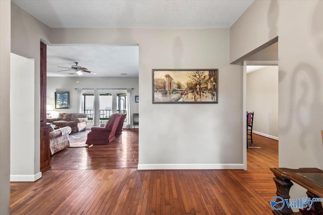 hall with baseboards, dark wood finished floors, and a textured ceiling