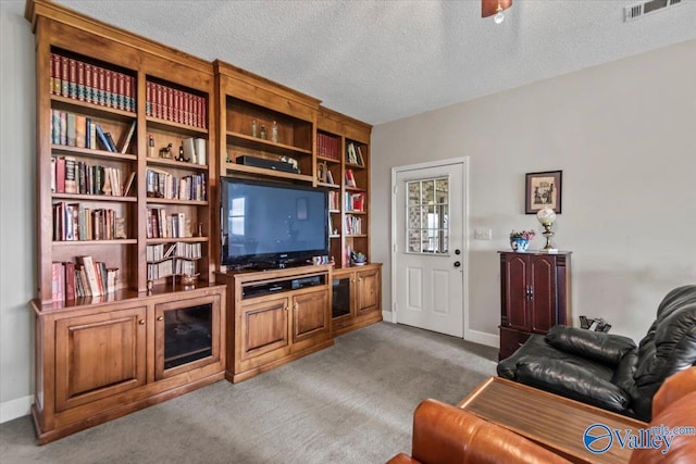 living area with baseboards, a textured ceiling, visible vents, and carpet flooring