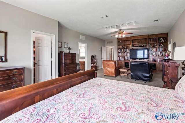 carpeted bedroom with track lighting, visible vents, and a textured ceiling