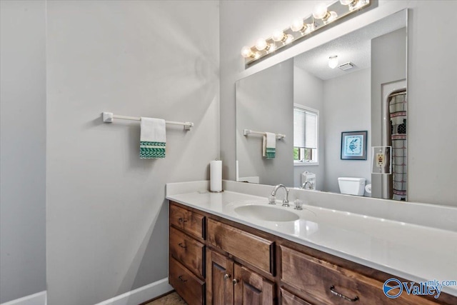 bathroom featuring baseboards, vanity, and toilet