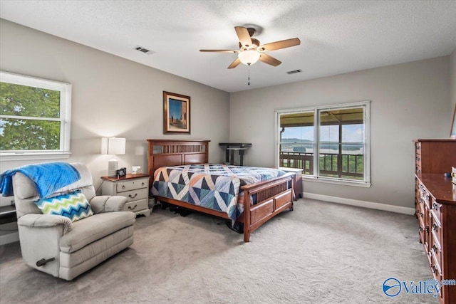 bedroom with carpet floors, visible vents, a textured ceiling, and baseboards