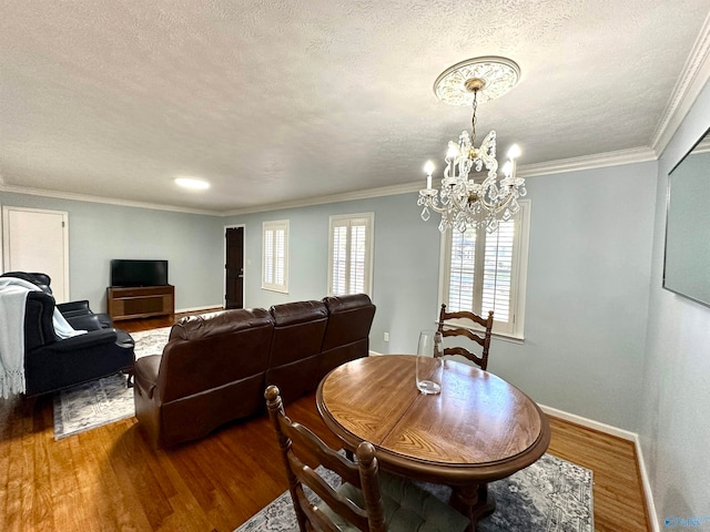 dining area featuring wood-type flooring, a textured ceiling, a chandelier, and ornamental molding