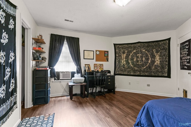 bedroom featuring cooling unit, a textured ceiling, and hardwood / wood-style floors