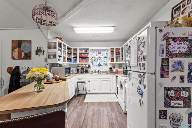 kitchen featuring light hardwood / wood-style flooring, white appliances, white cabinets, sink, and a textured ceiling