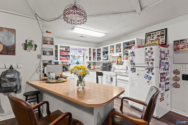 kitchen featuring white cabinets, wood-type flooring, a kitchen breakfast bar, and white appliances