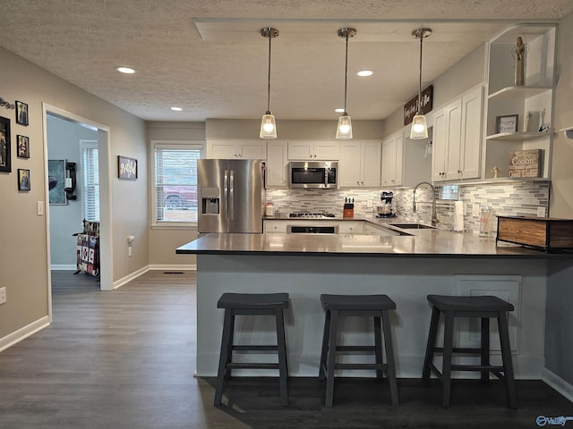 kitchen featuring appliances with stainless steel finishes, sink, white cabinetry, and pendant lighting