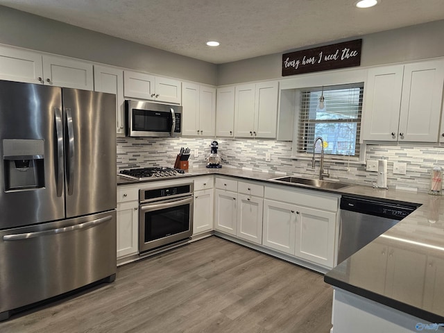 kitchen with white cabinets, light wood-type flooring, stainless steel appliances, and sink