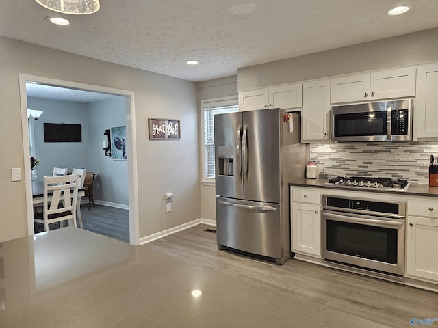 kitchen featuring appliances with stainless steel finishes, white cabinetry, backsplash, and a textured ceiling