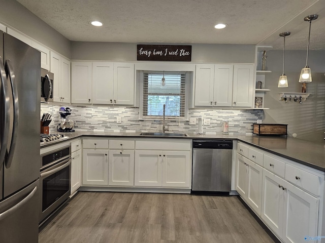 kitchen with sink, appliances with stainless steel finishes, white cabinetry, and light wood-type flooring