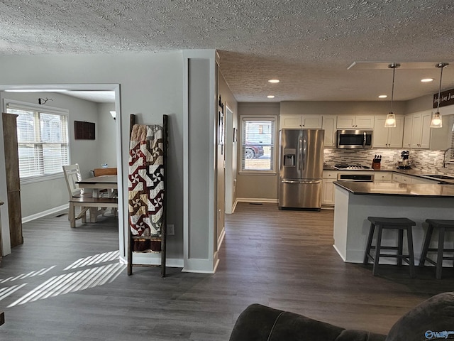 kitchen featuring sink, appliances with stainless steel finishes, white cabinetry, and decorative light fixtures