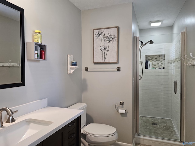 bathroom featuring toilet, vanity, and a shower with shower door