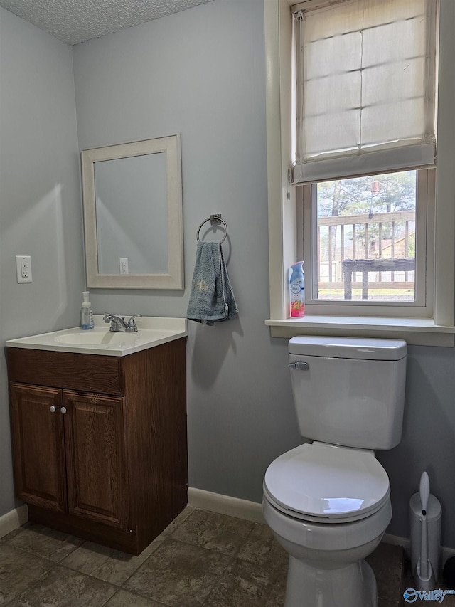 bathroom with toilet, vanity, and a textured ceiling