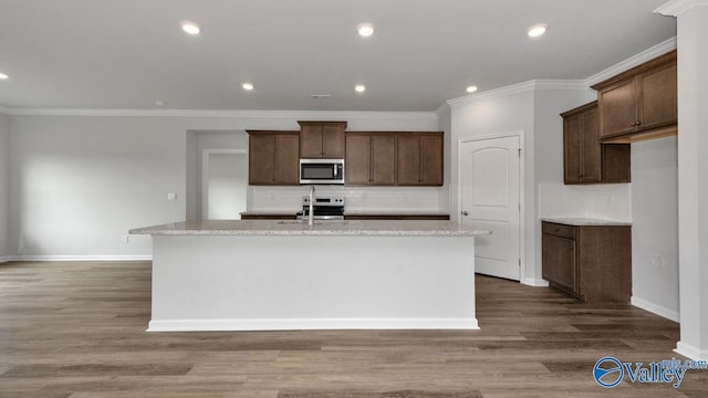 kitchen featuring a kitchen island with sink, sink, wood-type flooring, and stainless steel appliances